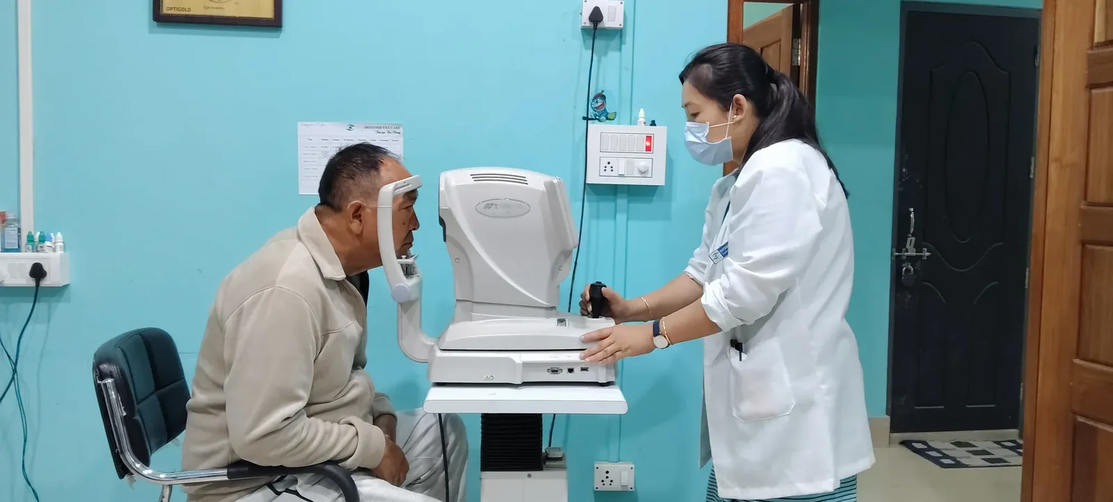 An optometrist guiding a patient through an autorefractor examination at Ibotombi Eye Care